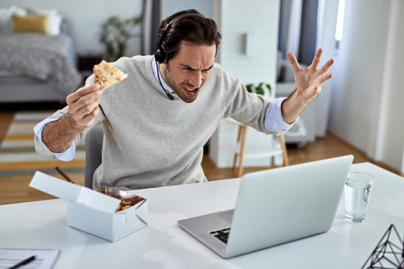 Image d'un homme énervé, mangeant devant son ordinateur, représentant le stress et l'alimentation au travail