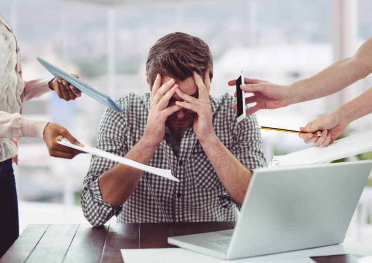 Image représentant un homme accablé de demandes venant du téléphone, de dossiers et de personnes. Symbolisation de l'état de stress reçu par la gestion de crise en entreprise.